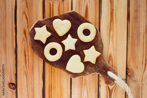 Beautiful set of homemade cookies stars and hearts on the brown decorative board, vintage cup of tea and honey. Sunny morning. Food, break, cooking, lifestyle concept. Top view. Close up.