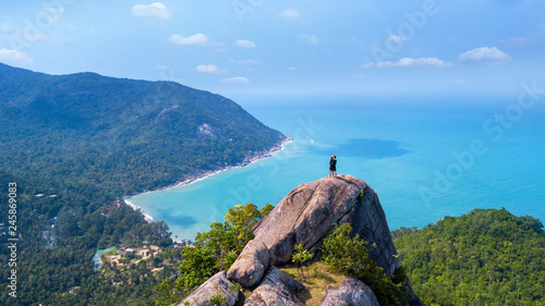 Man and woman standing on cliff's edge and looking into a sand beach of koh Phangan island,Thailand photo