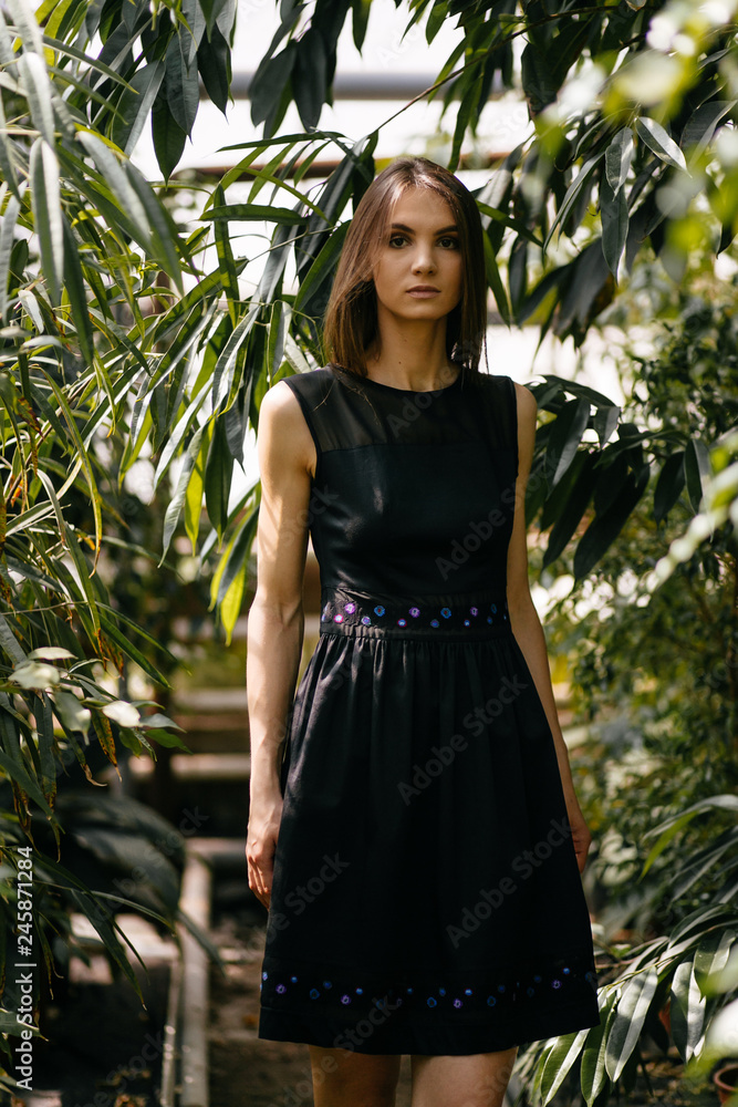 A young beautiful girl poses in a garden with exotic plants A young beautiful girl poses in a garden with exotic plants
