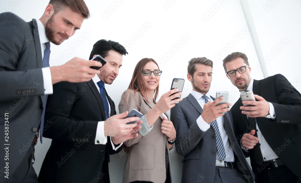 business team looking at the screens of their smartphones business team looking at the screens of their smartphones