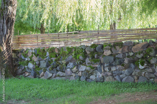 long solid rural fence made from aged stones and made of bamboo