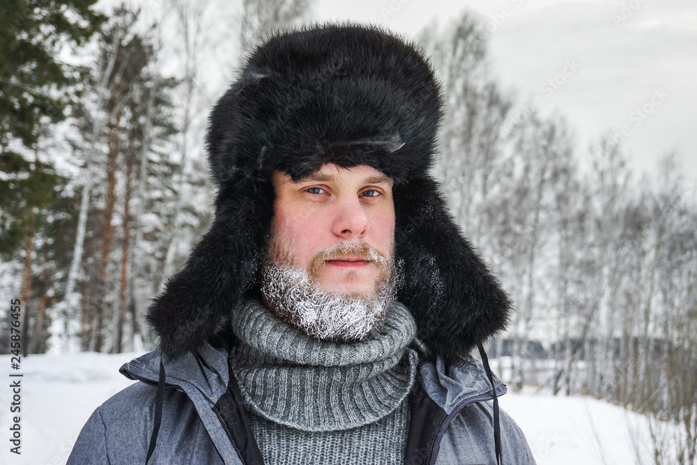 Siberian Russian man with a beard in hoarfrost in freezing cold in the  winter freezes in a village in a snowdrift and wears a hat with a earflap.  Stock Photo | Adobe