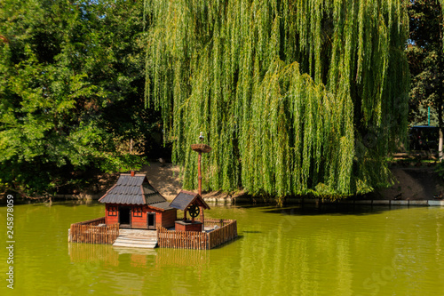 Wooden house for water birds and turtles on a lake in city park