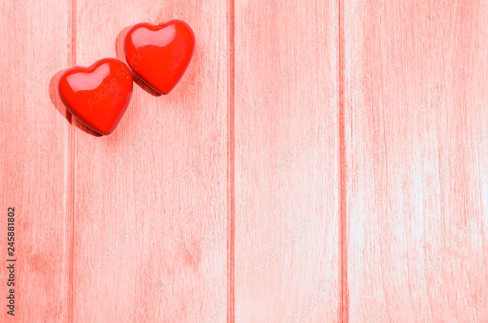 Couple of glossy red hearts for Valentine's day on living coral colored wooden table Couple of glossy red hearts for Valentine's day on living coral colored wooden table