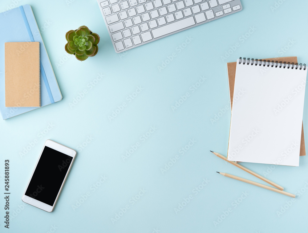 Top view of modern blue office desktop with blank notepad, computer, smartphone. Mock up, empty space Top view of modern blue office desktop with blank notepad, computer, smartphone. Mock up, empty space
