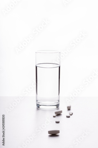 A glass of water on a white background and pills (drugs)