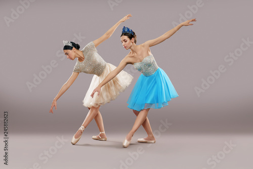 Side view of two dancers dancing and bending down in studio