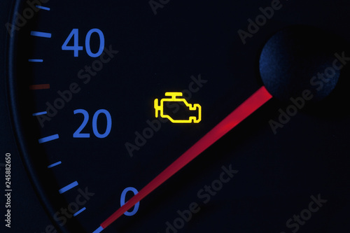 yellow engine check engine icon on car dashboard, black background
