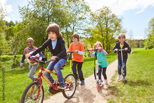 Kinder machen Wettrennen mit Roller und Fahrrad