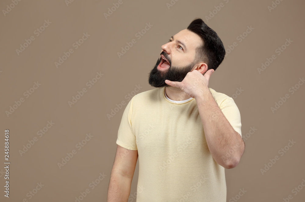 cute brunette with beard in yellow t-shirt simulates a phone conversation cute brunette with beard in yellow t-shirt simulates a phone conversation