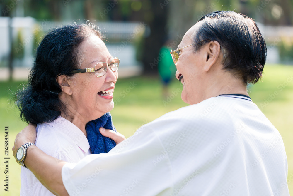 Smiling man wiping sweat of her wife with napkin after exercising in the park Smiling man wiping sweat of her wife with napkin after exercising in the park