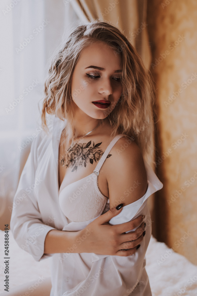 Naklejka premium Beautiful girl in a white shirt on the bed