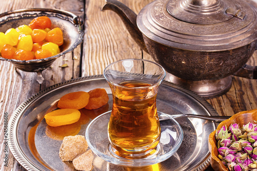 various dried fruits and Turkish tea in Armudu glass on wooden table.