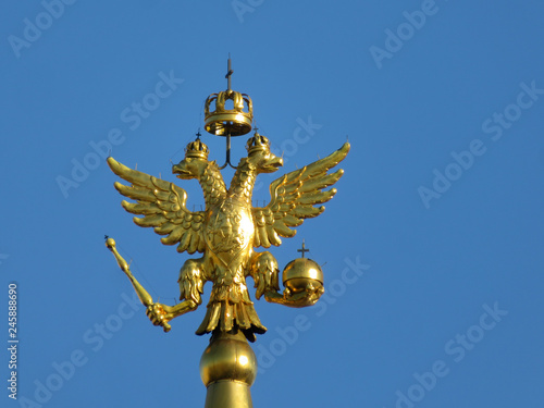 Double-headed eagle, symbol of Russia isolated on blue sky background. Golden russian emblem on the top of tower on Red square in Moscow
