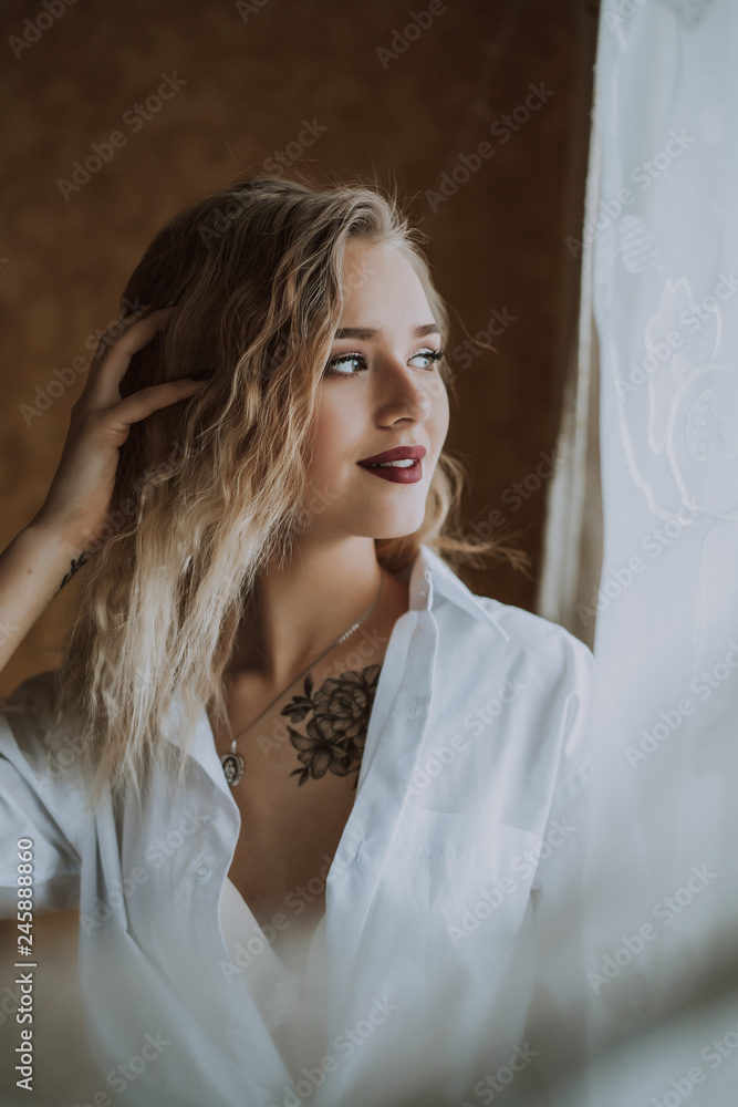 Beautiful girl in a white shirt by the window Beautiful girl in a white shirt by the window