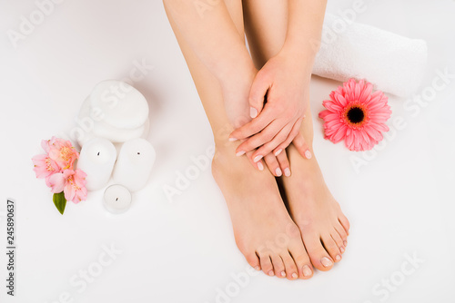 Partial shot of woman sitting on white surface and touching legs