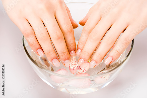 Cropped view of woman taking nail bath in glass bowl