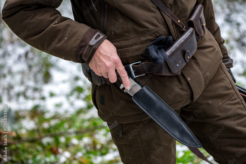 the hunter pulls out a knife in the winter forest the hunter pulls out a knife in the winter forest