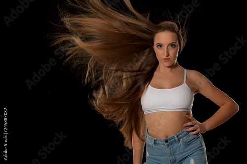 Young woman with very long flying hair on black background