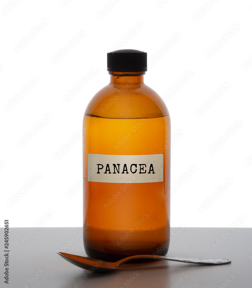 Panacea, magic potion. Old brown glass medicine bottle with spoon, label. Pharmaceutical concept or ironic metaphor, wishful thinking. White behind. Panacea, magic potion. Old brown glass medicine bottle with spoon, label. Pharmaceutical concept or ironic metaphor, wishful thinking. White behind.