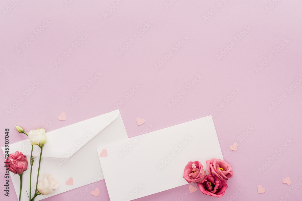 top view of empty card, paper hearts and envelope isolated on pink