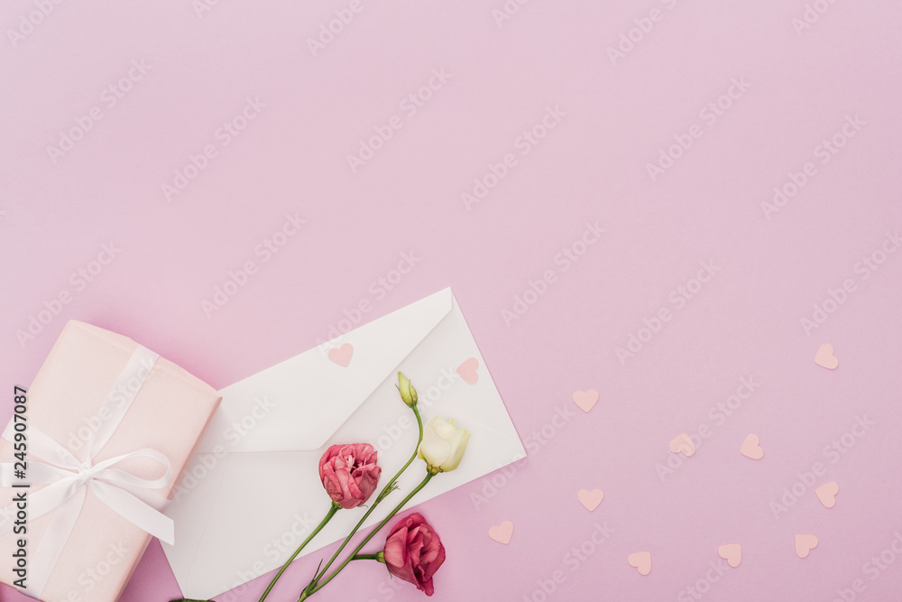 top view of envelope, gift box, flowers and paper hearts isolated on pink top view of envelope, gift box, flowers and paper hearts isolated on pink