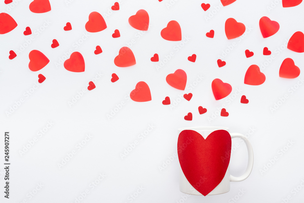top view of paper hearts and cup with heart shaped sticker isolated on white, st valentines day concept