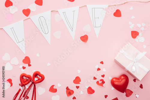top view of valentines decorations and paper garland with 'love' lettering isolated on pink, st valentines day concept
