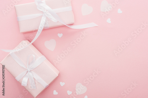 top view of gift boxes with ribbons and paper hearts isolated on pink with copy space © LIGHTFIELD STUDIOS