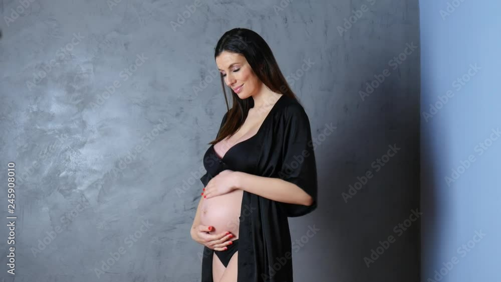 A pregnant young woman wearing lingerie at home.
A pregnant young woman wearing lingerie at home.