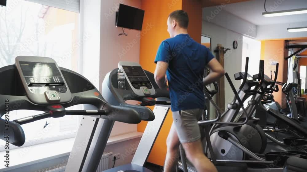 Unrecognizable man running on the treadmill in the fitness studio. Tilt long shot Unrecognizable man running on the treadmill in the fitness studio. Tilt long shot