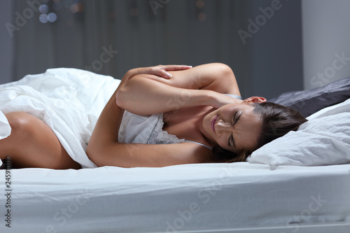 Woman suffering neck ache sleeping with a bad pillow photo