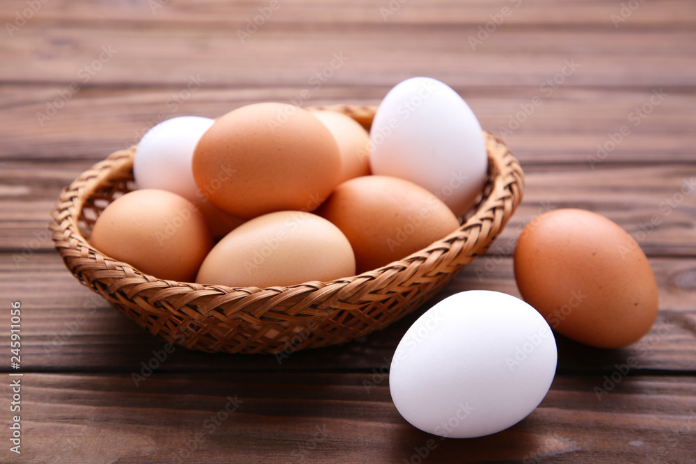 Chicken eggs in basket on brown wooden background Chicken eggs in basket on brown wooden background