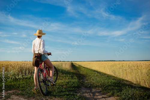 Fototapeta Naklejka Na Ścianę i Meble -  Young woman on bicycle in fields