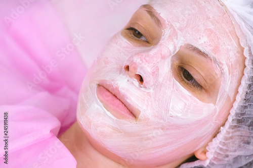 Woman face with moisturizing mask on the cosmetology procedure. Face close-up.