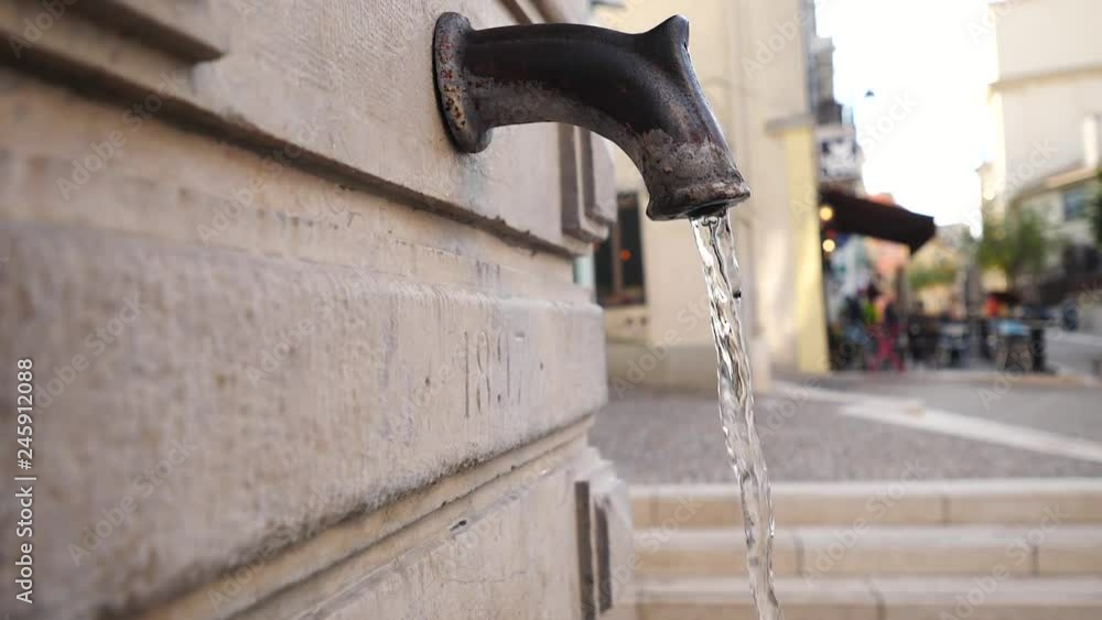 Jet of water pours from old street tap on background street landscape Cannes