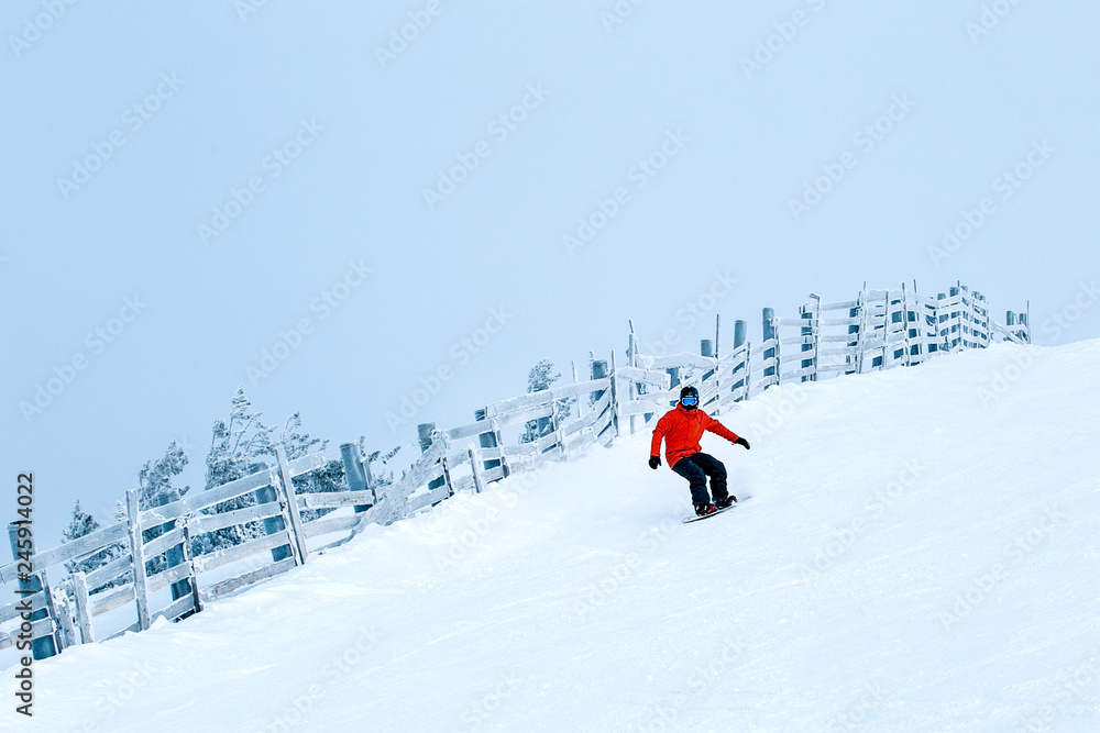 Young man snowboarder running down the slope. Winter sport and recreation, leisure outdoor activities.