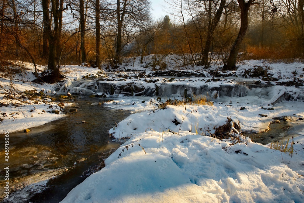 Frozen sluice and stream in snowy landscape with trees. Frozen sluice and stream in snowy landscape with trees.