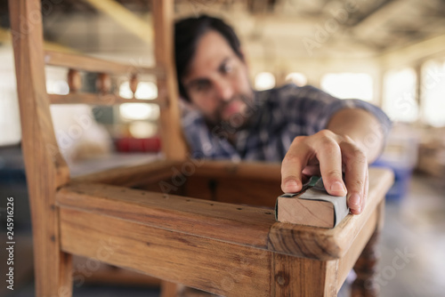 Tableau sur toile Skilled woodworker sanding a chair in his workshop