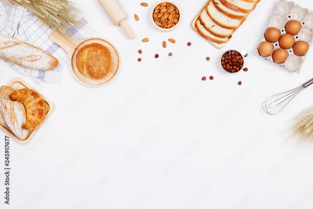 Homemade breads or bun, croissant and bakery ingredients, flour, almond nuts, hazelnuts, eggs on white background, Bakery background frame, Cooking breakfast concept. Flat lay, Top view and copy space Homemade breads or bun, croissant and bakery ingredients, flour, almond nuts, hazelnuts, eggs on white background, Bakery background frame, Cooking breakfast concept. Flat lay, Top view and copy space