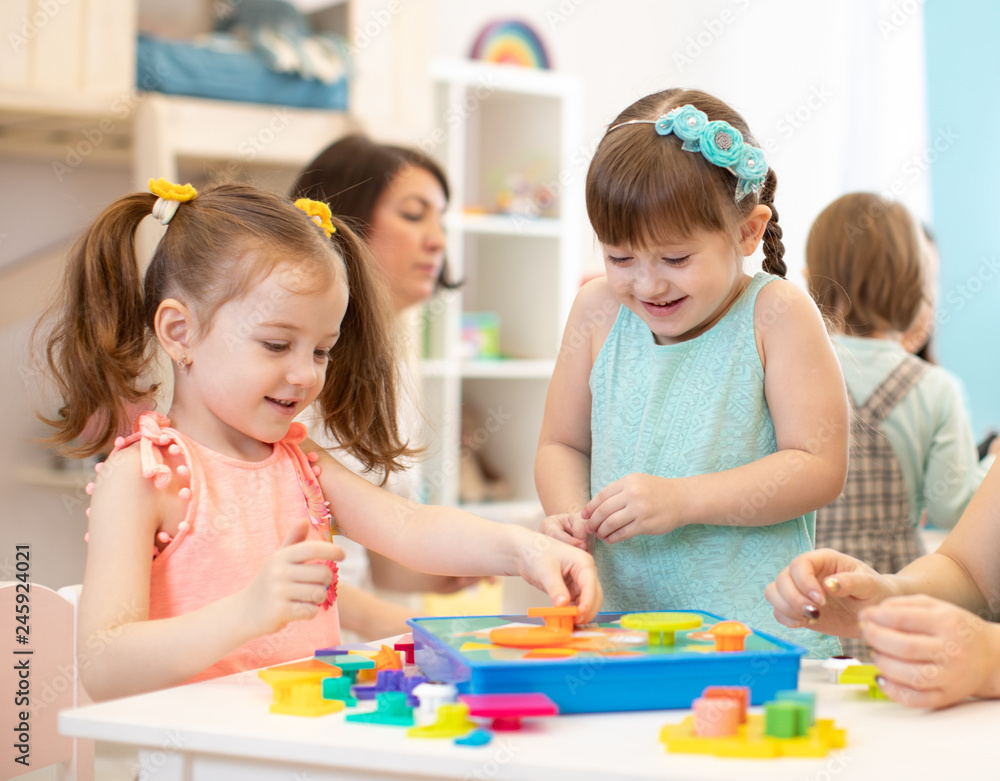 Fototapeta premium Happy children playing with plastic building blocks at kindergarten