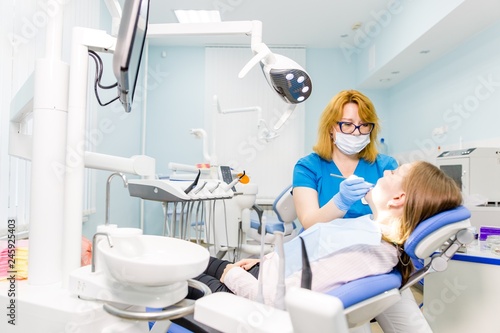 Woman with glasses dentist treats dental caries a young girl at the clinic care for the oral cavity