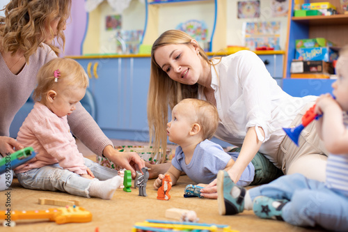 babies playing with toys sitting on floor in nursery or kindergarten