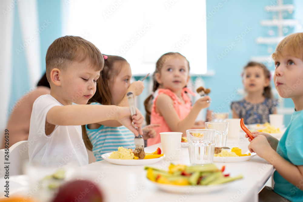 Group of kids enjoying healthy lunch in kindergarten