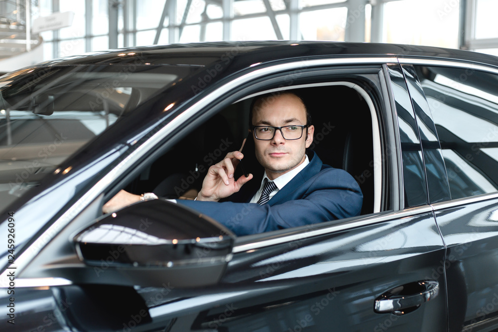 Businessman sitting inside the cabin of a black car talking on the phone Businessman sitting inside the cabin of a black car talking on the phone
