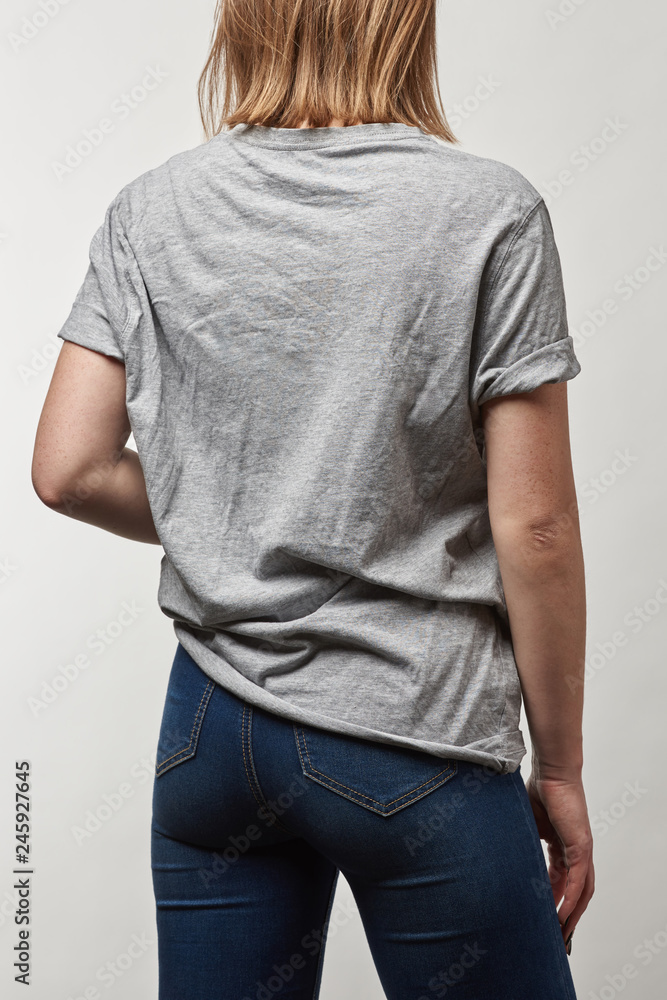 back view of young woman in basic grey t-shirt with copy space isolated on white back view of young woman in basic grey t-shirt with copy space isolated on white