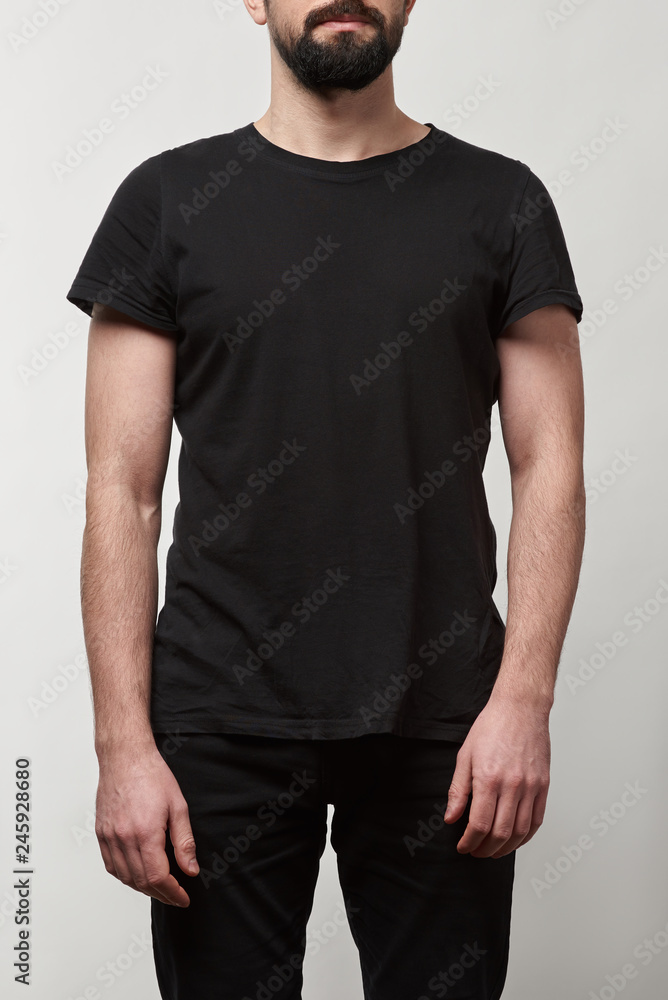 partial view of bearded man in black t-shirt with copy space isolated on grey partial view of bearded man in black t-shirt with copy space isolated on grey