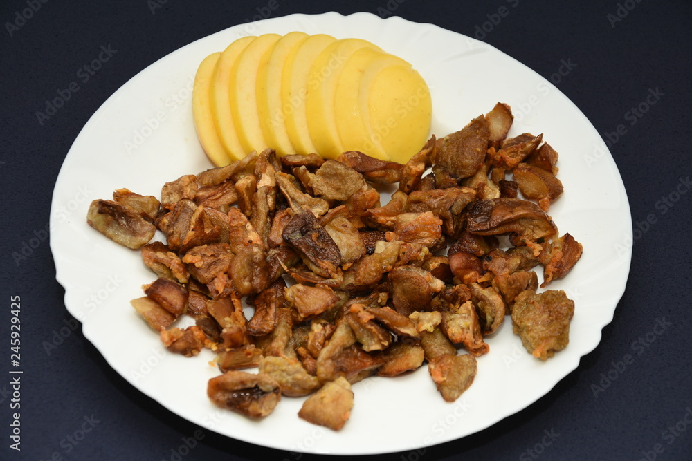 mushrooms fried with goldene apples sliced on a white plate
