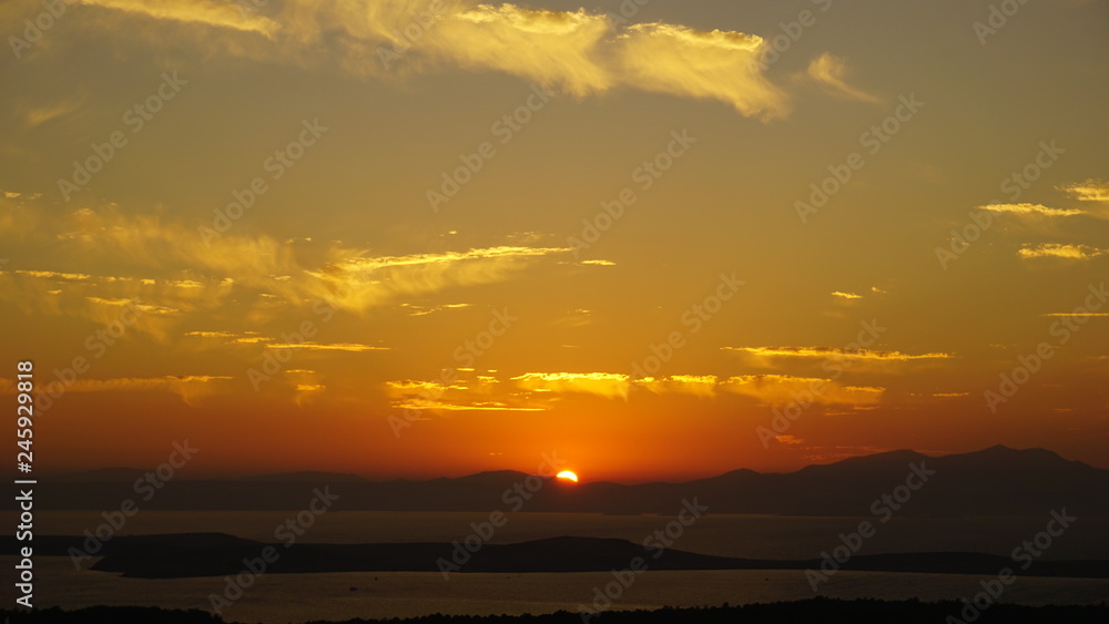 Sunset over sea at Devil's Table (Şeytan Sofrası). Bright dramatic sky and dark blue ground. Beautiful landscape under scenic colorful orange sky at sunset. Sun over skyline. Warm yellow color concept