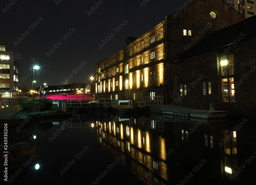 number one lock on the leeds canal at night near granary wharf with victoria bridge and illuminated buildings reflected in the water